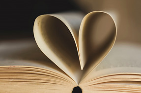 An opened book with the 2 top pages curved inward to make the shape of a heart. 
