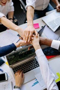 Employees at their computers joining hands. 