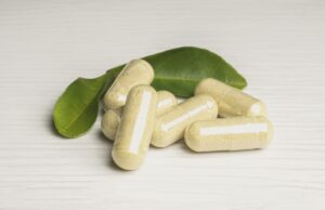 A cluster of supplement capsules and green leaves. 