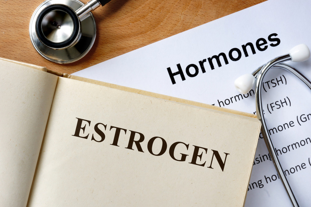 An opened book with the word estrogen on it placed on a piece of paper that says hormones with a stethoscope on it. 
