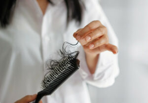 A woman holding a hair brush that has a lot of hair in it. 