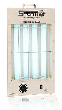 A Sperti vitamin D lamp that is tan and rectangular with 4 light blue cylindrical bulbs in the middle of it and a black circular dial at the bottom and a silver handle at the top.