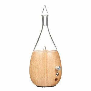 A glass essential oil diffuser with a glass top and wooden bottom that is in the shape of a raindrop.