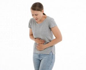 A woman hunched over holding her abdomen in pain. 