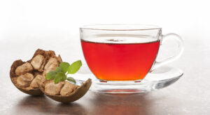 A glass mug of monk fruit tea with a monk fruit next to it. 