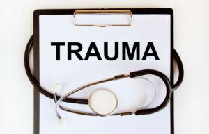 The word trauma written on a piece of paper on a clipboard with a stethoscope wrapped around it.