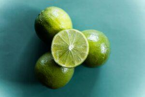 3 whole limes with a slice of lime resting on top of them in the middle. 