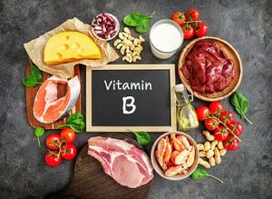 A small chalkboard with vitamin B written on it surrounded by foods high in B complex vitamins.