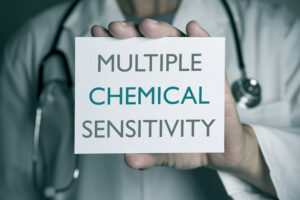 A doctor holding a sign that says Multiple Chemical Sensitivity.