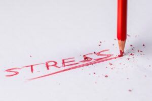 A red colored pencil writing the word stress. 