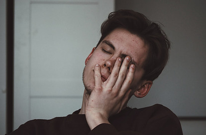 A man with his hand on his face with a headache feeling unwell.