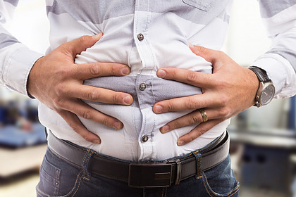 A man with his hands on his abdomen experiencing bloating.