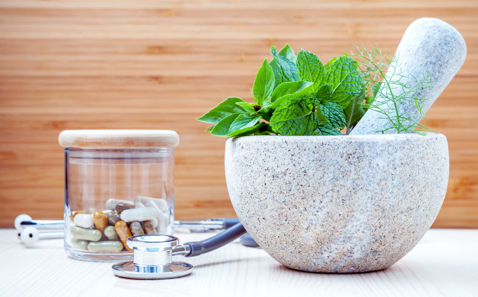 A mortar and pestle with supplements and a stethoscope.