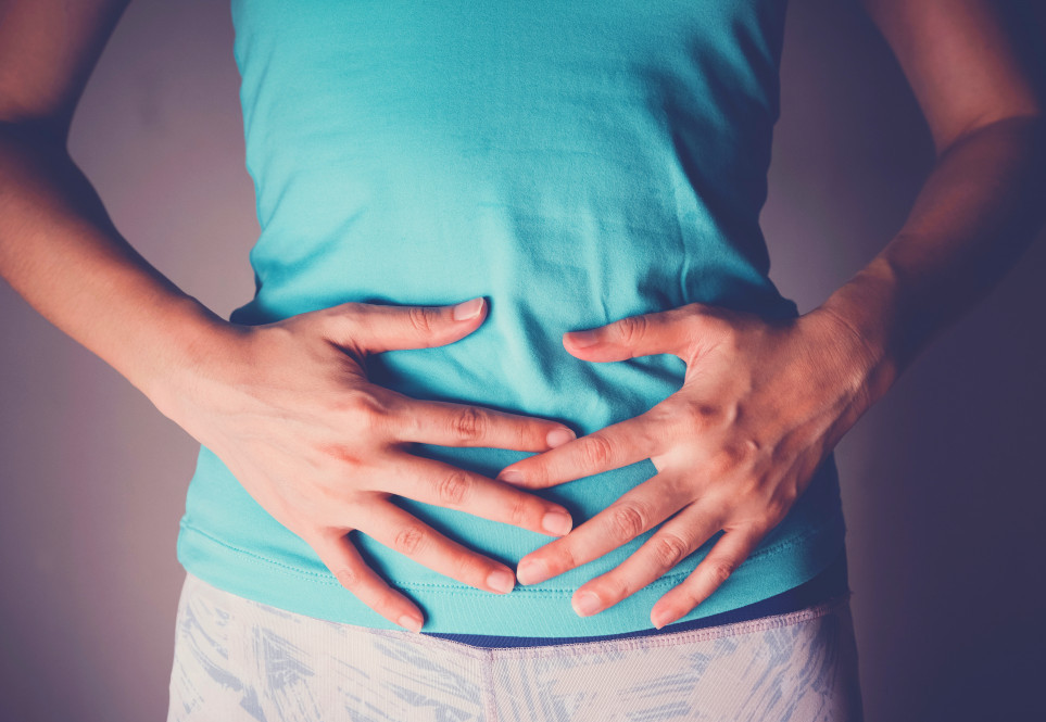 A woman with her hands on her abdomen.